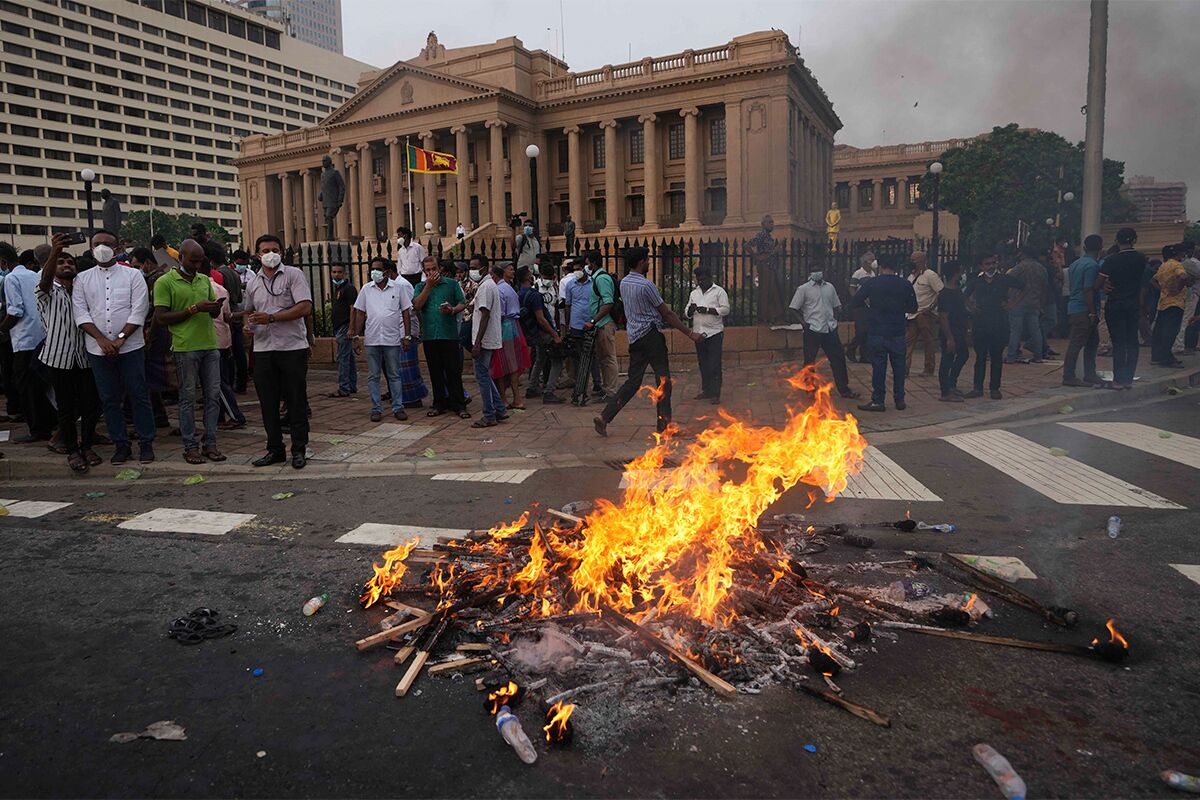 Протестующие сжигают транспаранты напротив президентской администрации в Коломбо