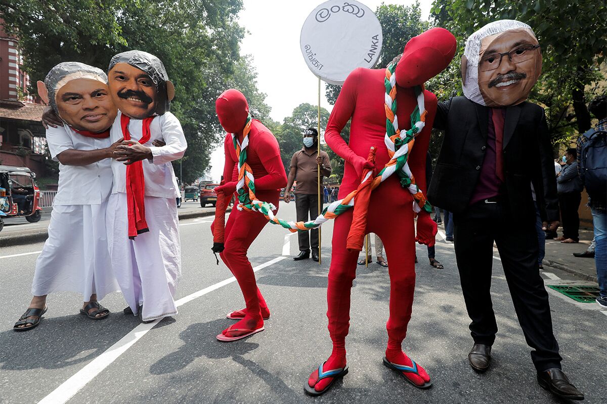 Протестующие в масках президента страны Готабаи Раджапаксы и его родственников, министра финансов Басиля и экс-премьера Махинды Раджапаксы