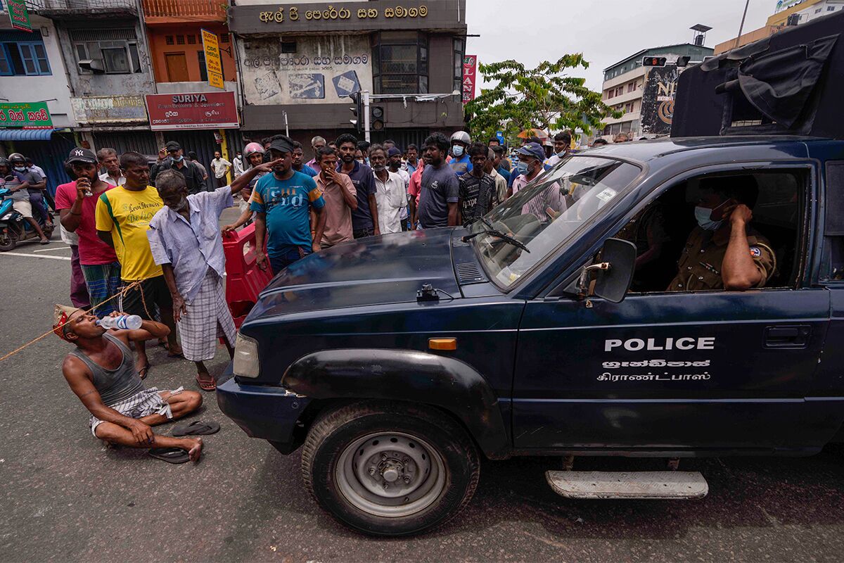 Протестующие пытаются остановить полицейскую машину во время демонстраций в Коломбо 