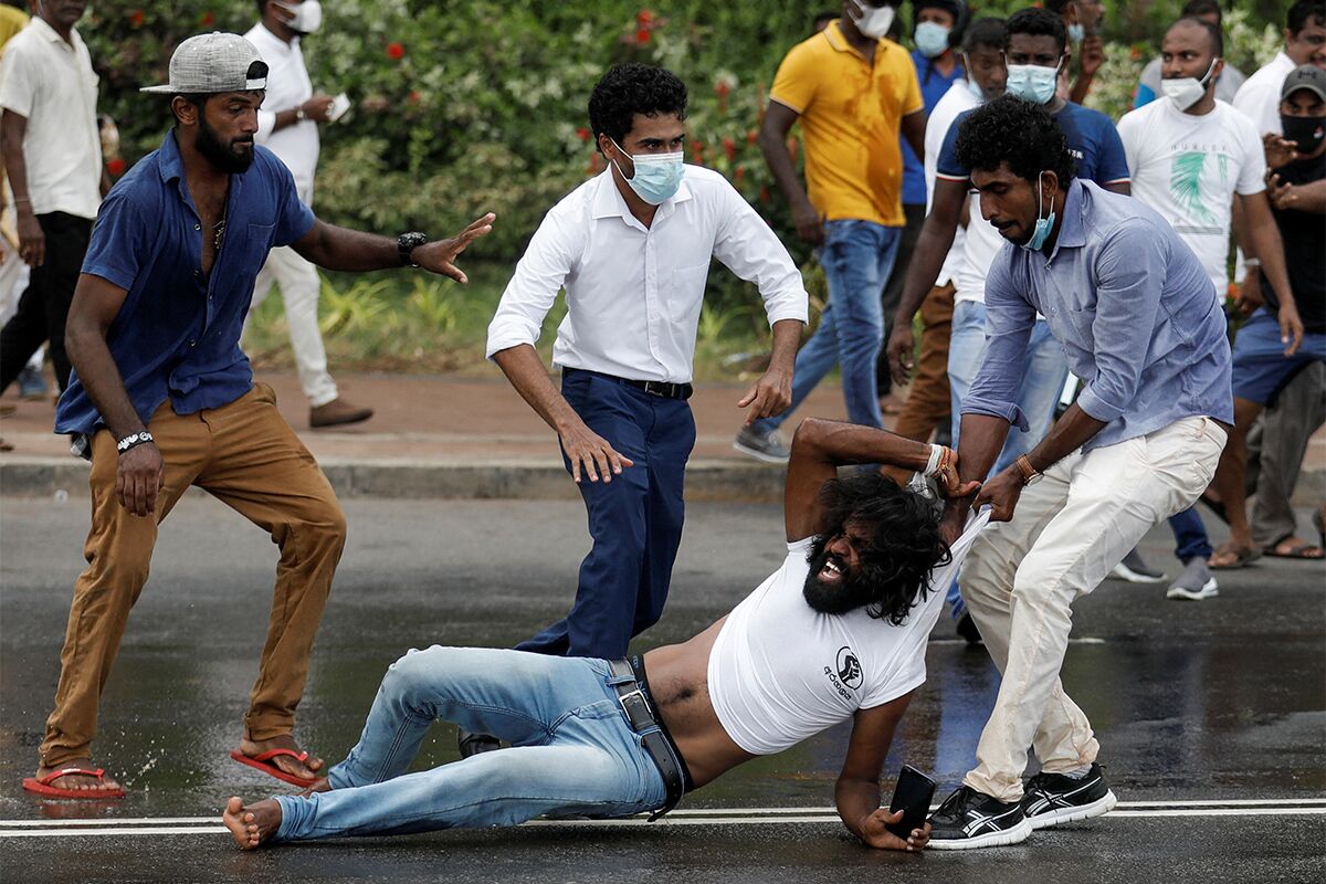 Сторонник правящей партии Шри-Ланки тащит участника антиправительственных митингов