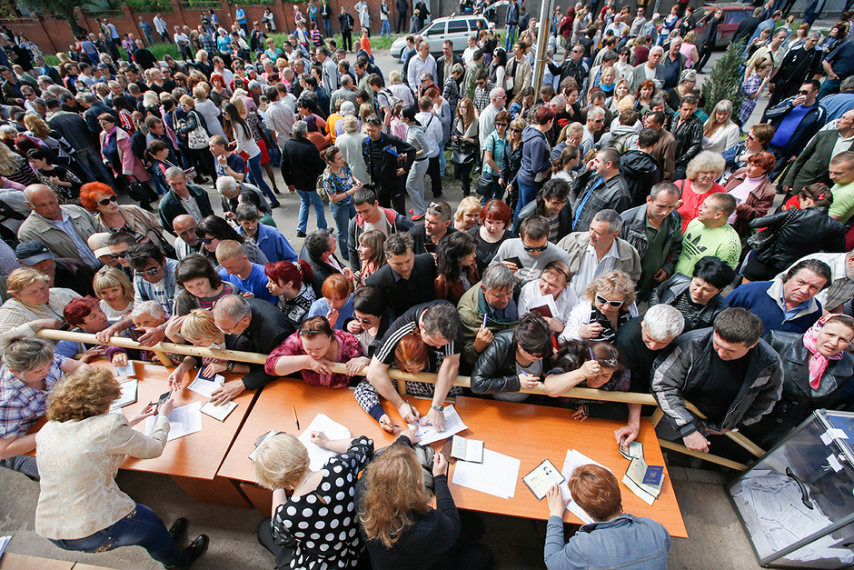 Жители Мариуполя стоят в очереди, чтобы получить бюллетени от членов местной избирательной комиссии во время референдума о статусе Донецкой области, 11 мая 2014 года
