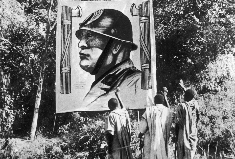 Эфиопы приветствуют итальянский плакат с изображением Бенито Муссолини. Эфиопия, Мэкэле, ноябрь 1935 года