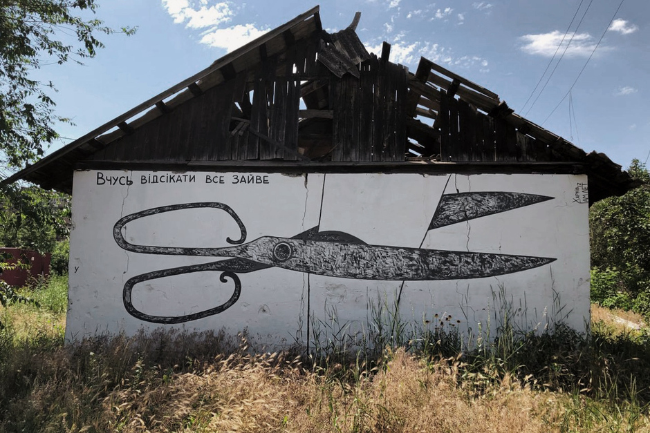Граффити «Учусь отсекать все лишнее» на заброшенном здании в центре Изюма 
