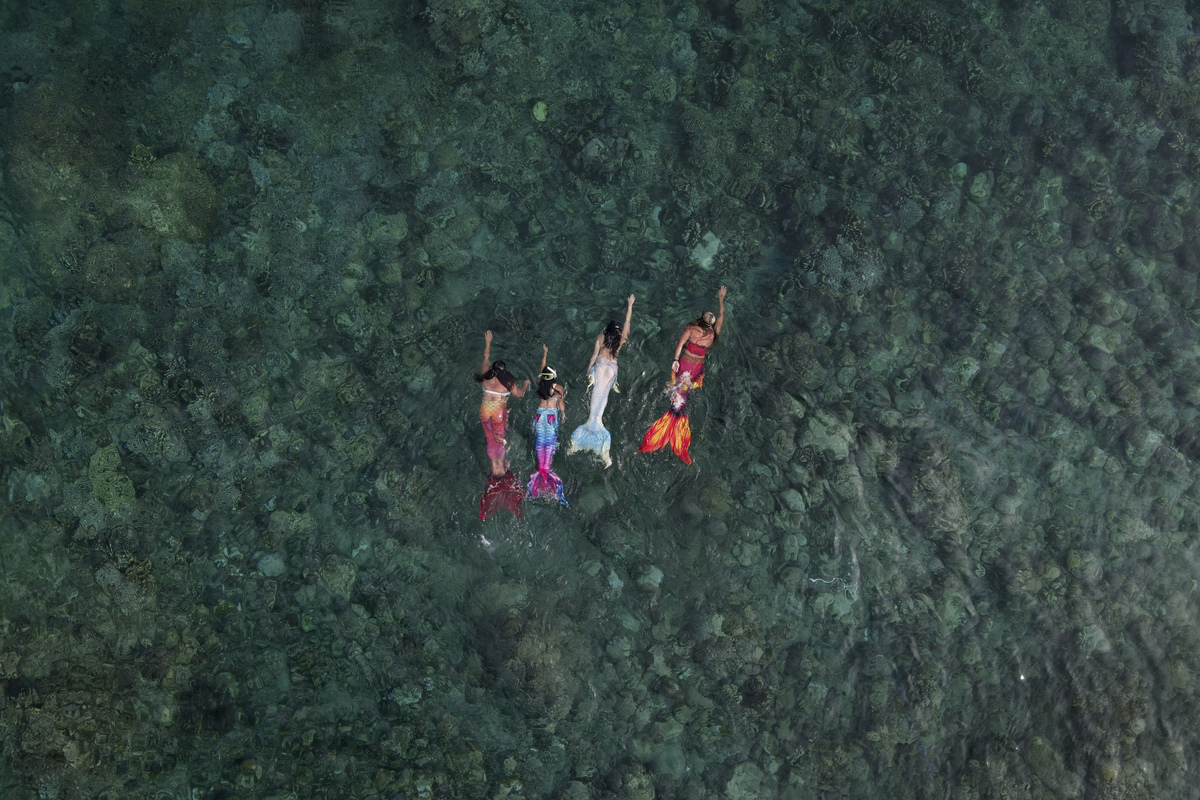 Квин Пангке Табора (крайняя справа) плавает с ученицами-русалками во время урока в Мабини. Слева направо: Шела Кандадо, Дженника Секуя и Мерил Луиза Реке. Май 2022 года