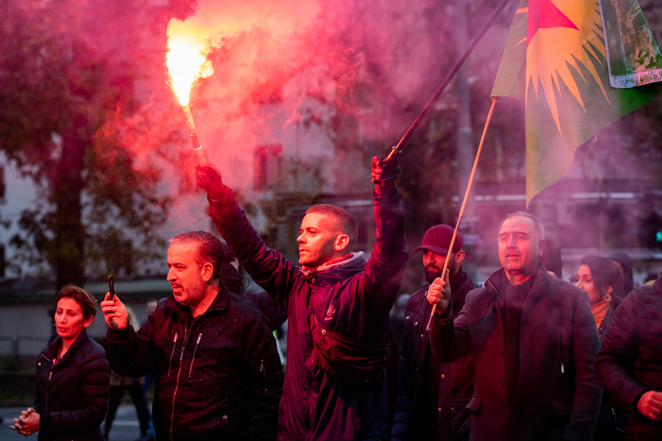 Акция протеста против турецкого вторжения в Сирию в Гётеборге, Швеция. Один из мужчин держит в руках флаг Союза общин Курдистана — зеленое полотнище с желтым солнцем, в центре которого красная звезда. 13 октября 2019 года