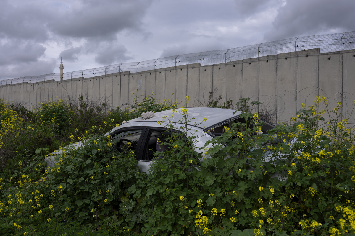 Брошенная машина возле стены в районе города Бака Аль-Гарбийе, отделенного от соседней деревни Назлат Исса на Западном берегу 