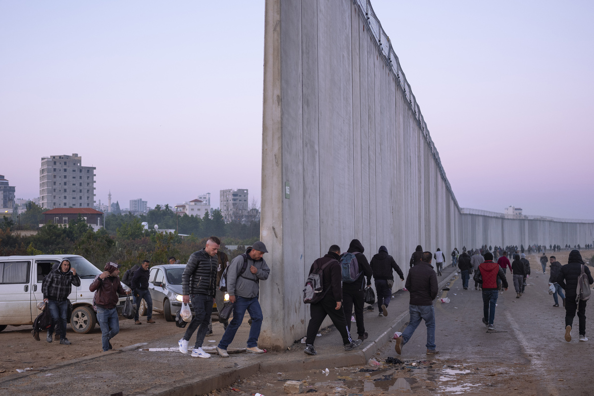 Палестинцы пересекают стену в районе между городом Калькилия на Западном берегу и израильским кибуцем Эяль