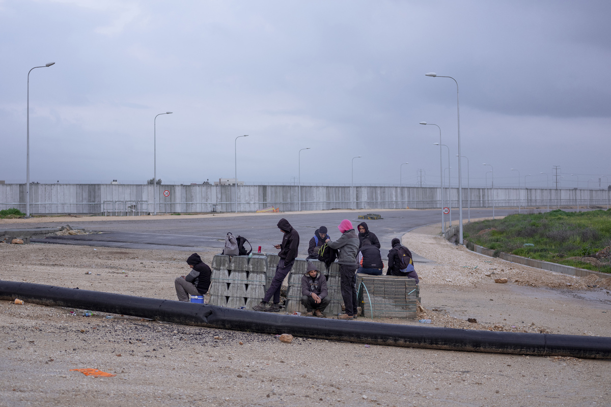 Палестинские рабочие ждут транспорта после перехода в Израиль с Западного берега на КПП Эяль