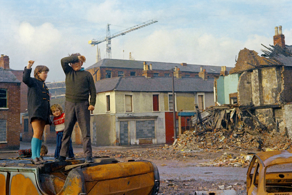 Дети играют на поврежденных автомобилях перед разрушенными домами в Белфасте, столице Северной Ирландии, февраль 1972 года