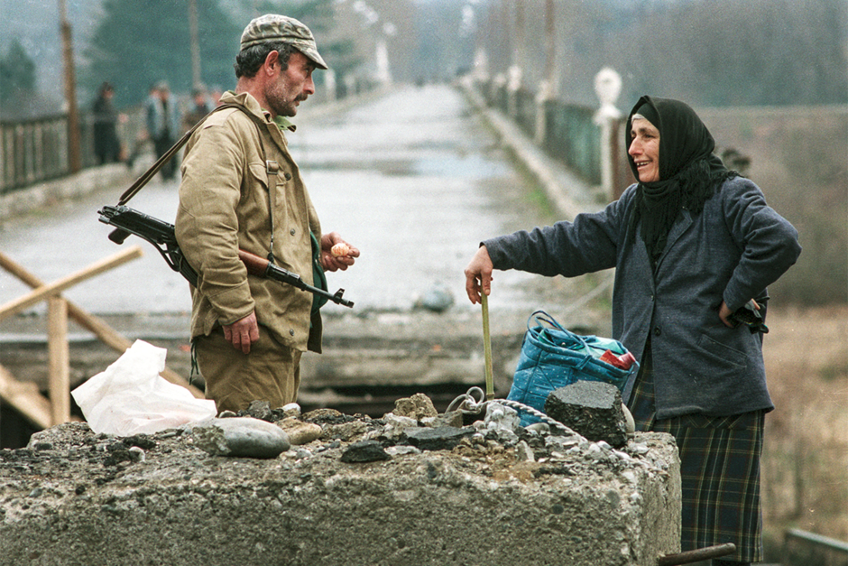 Абхазский солдат общается с местной жительницей рядом с разрушенным мостом через реку Ингури, отделяющим Абхазию от Грузии, февраль 1994 года