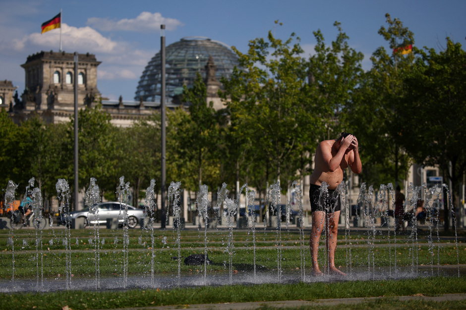 Мужчина охлаждается в фонтане перед зданием Рейхстага в Берлине, Германия