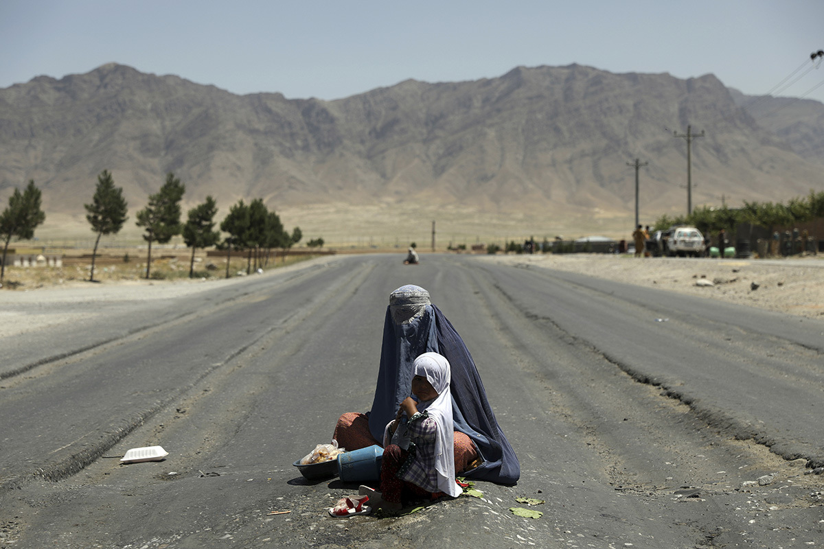 Афганская женщина просит милостыню на шоссе Баграм — Кабул, к северу от Кабула