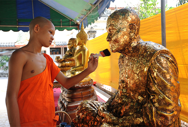 Послушник в монастыре очищает статую почетного монаха