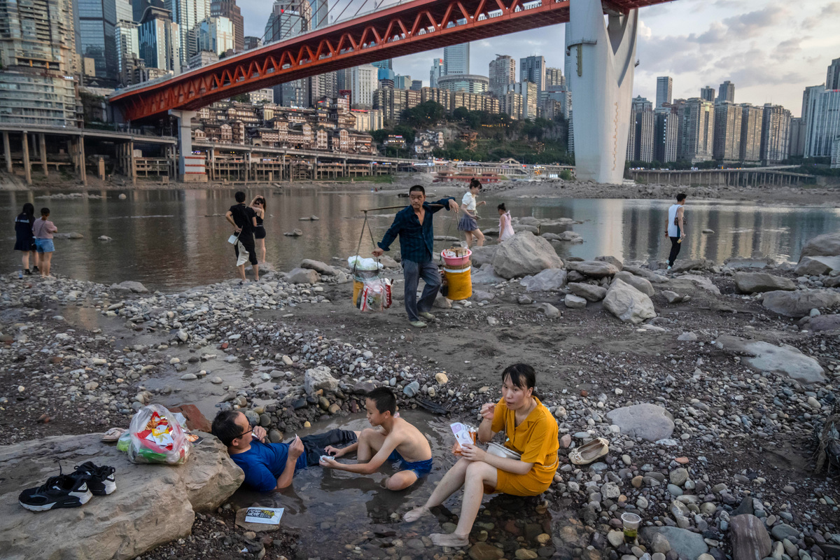 Люди сидят на дне Цзялинцзяна — высохшего русла левого притока реки Янцзы