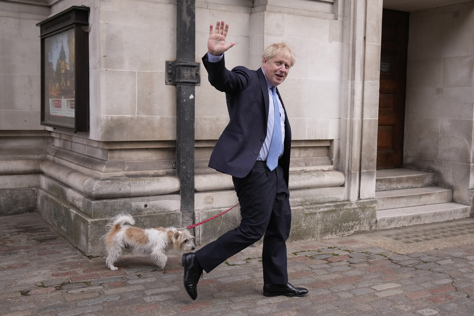 Премьер-министр Великобритании Борис Джонсон приветствует журналистов во время прогулки со своей собакой Дилин, 5 мая 2022 года