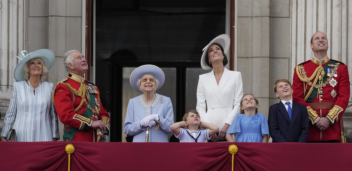 Королева в окружении семьи на праздновании платинового юбилея: слева — принц Чарльз с супругой Камиллой, справа — принц Уильям с супругой Кэтрин и детьми принцем Джорджем, принцессой Шарлоттой и принцем Луи. Букингемский дворец, 2 июня 2022 года. 