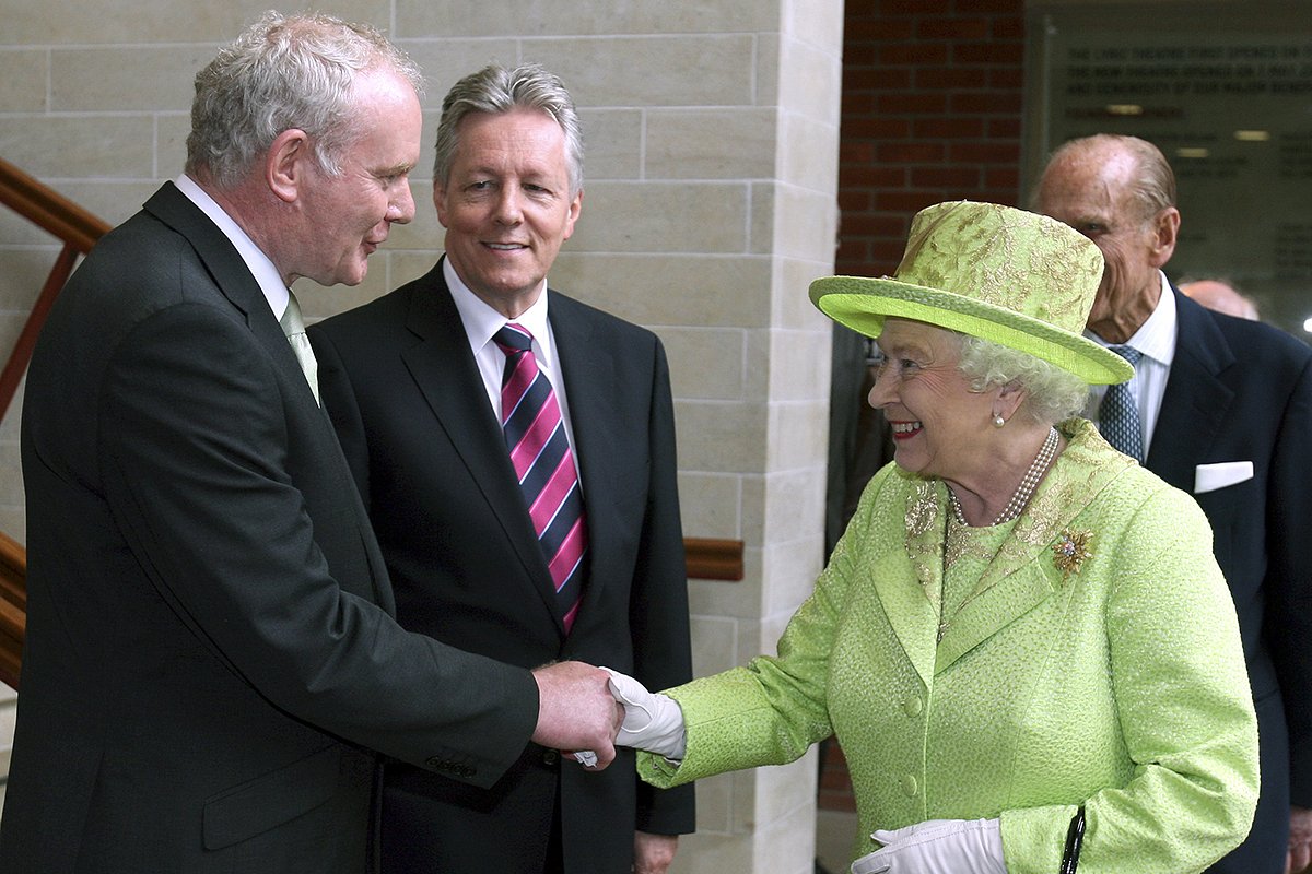 Королева Великобритании Елизавета пожимает руку заместителю первого министра Северной Ирландии Мартину Макгиннессу, рядом с которым стоит первый министр Питер Робинсон. Белфаст, 27 июня 2012 года.
