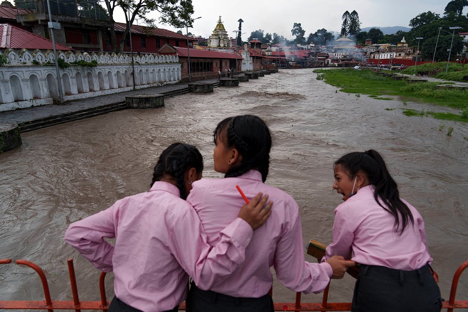 Школьницы смотрят на разлив Багмати после муссонных дождей. 27 июля 2022 года