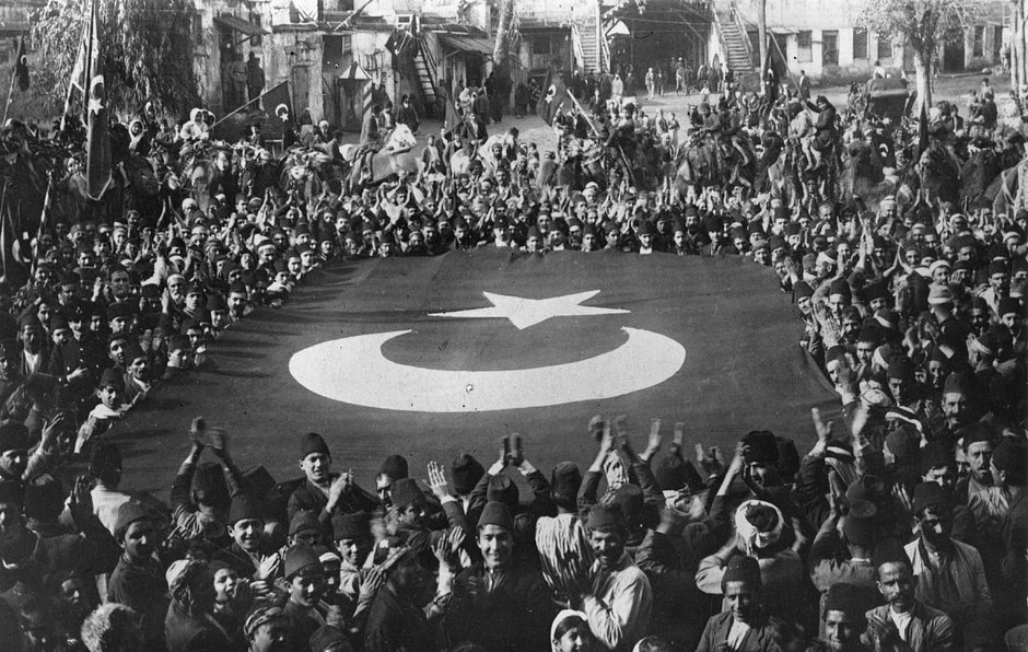 Толпа аплодирует большому турецкому флагу, сотканному в честь победы при Смирне