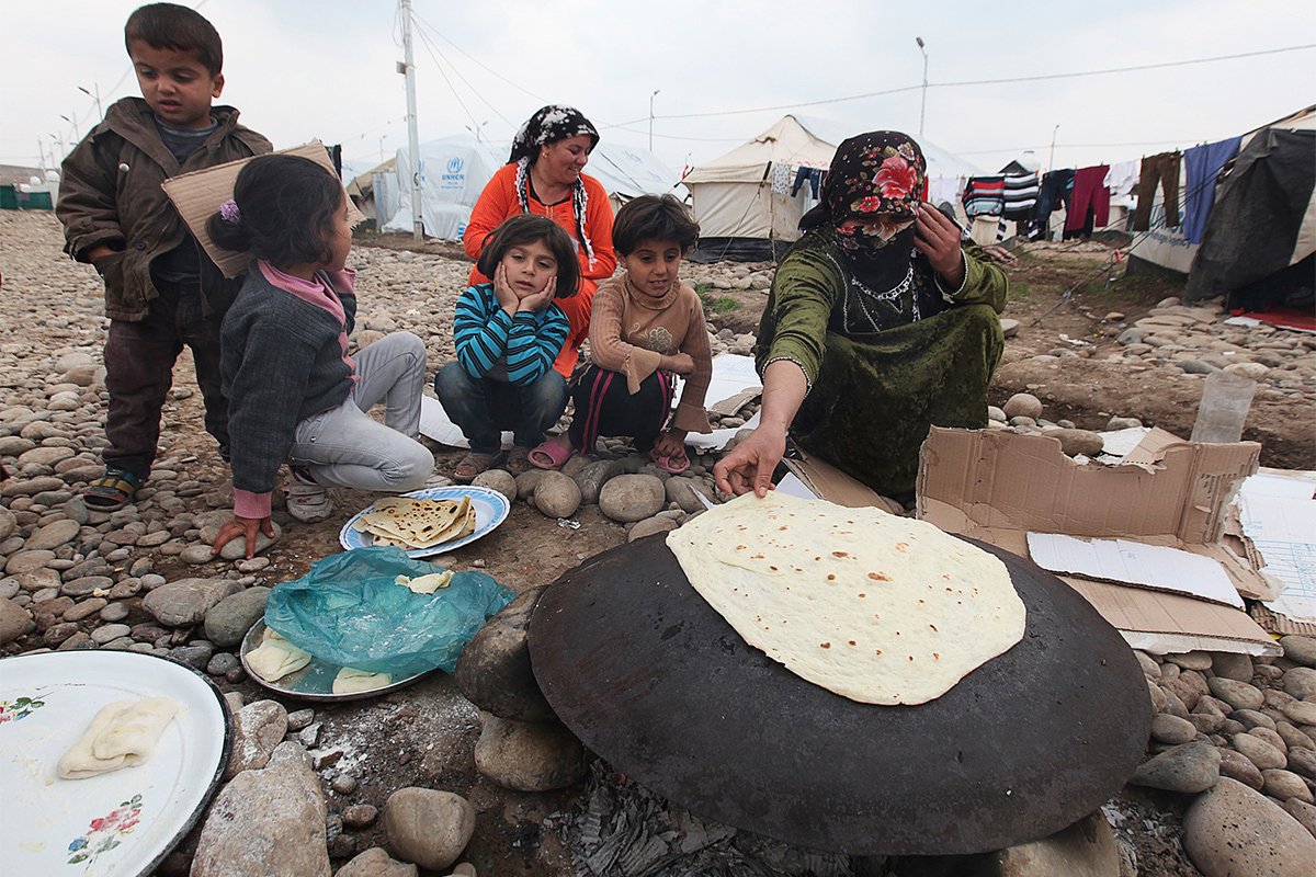 Сирийская беженка готовит хлеб в лагере на окраине города Эрбиль, Ирак