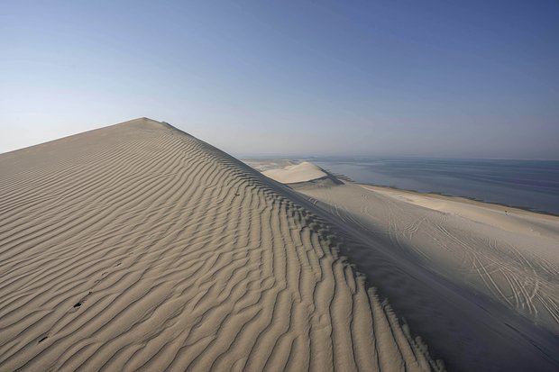 Песчаные дюны встречаются с водами залива Эль-Удайд. Достопримечательность расположена в 60 километрах от Дохи. Фото: Nariman El-Mofty / AP