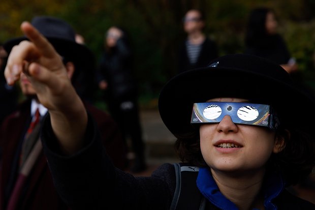 Жители Варшавы наблюдают солнечное затмение в октябре 2022 года. Фото: Michal Dyjuk / AP Photo