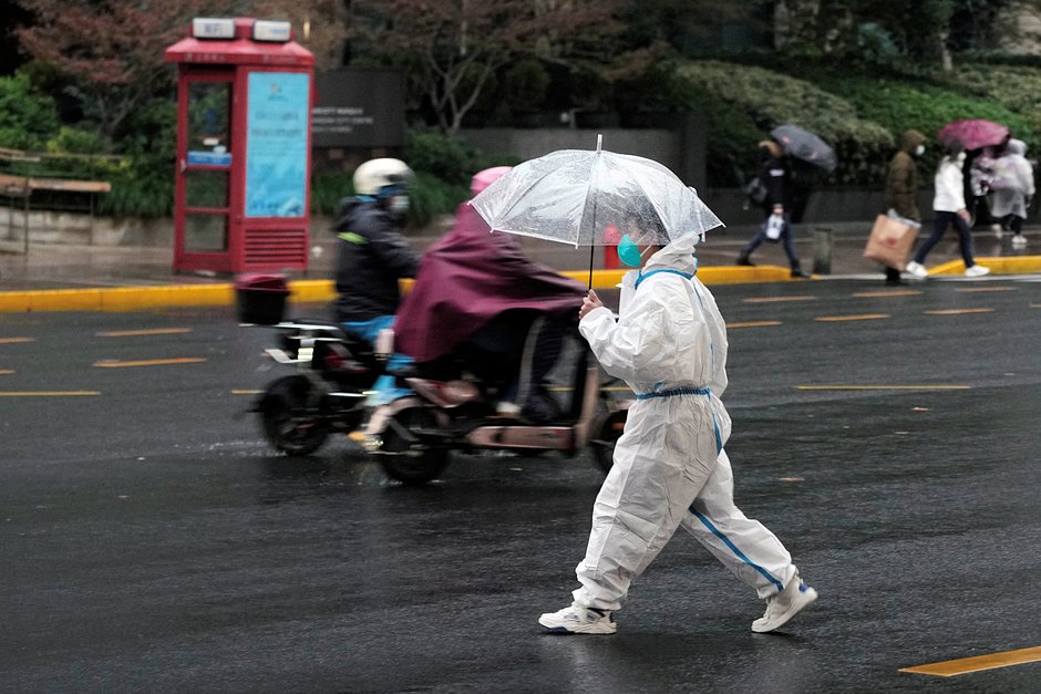 Человек в защитном костюме переходит дорогу во время вспышки COVID-19 в Шанхае, 30 ноября 2022 года