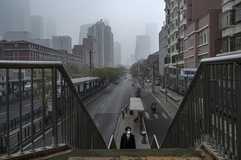 Мужчина в маске идет в одиночестве по эстакаде рядом с почти пустой улицей возле Центрального делового района, 24 ноября 2022 года, Пекин
