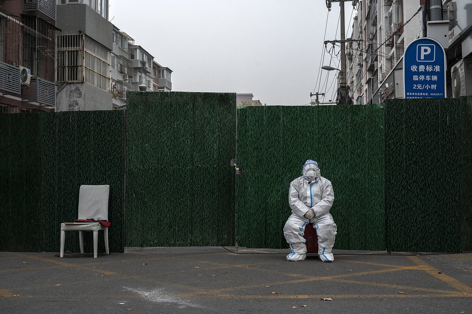 Сотрудник по борьбе с COVID-19 в защитном костюме охраняет вход в зону, закрытую с целью предотвращения распространения COVID-19, 24 ноября 2022 года, Пекин