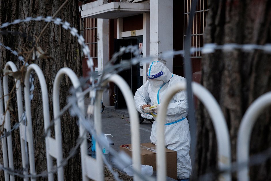 Сотрудник по борьбе с пандемией работает в защитном костюме в частично закрытом жилом комплексе в Пекине, 30 ноября 2022 года