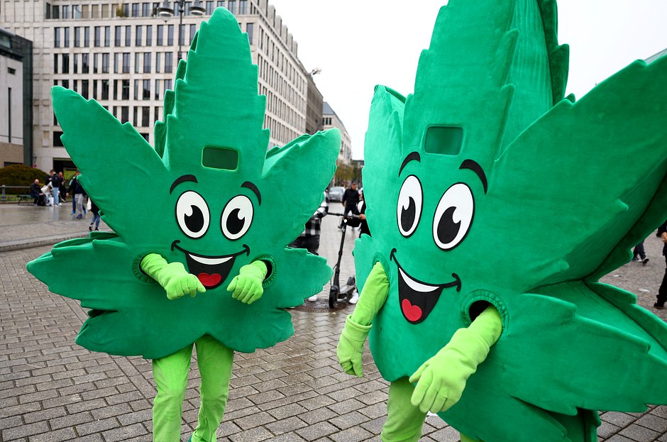 Люди, одетые в костюмы с изображением листьев каннабиса на митинге в честь ежегодного Всемирного дня каннабиса перед Бранденбургскими воротами в Берлине, Германия, 20 апреля 2022 года