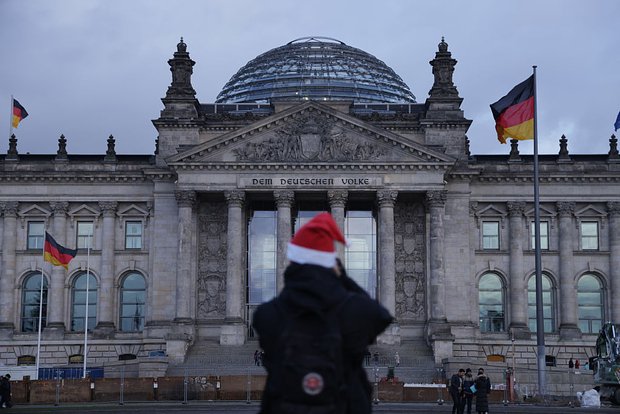 Мужчина в шляпе Санта Клауса стоит возле Рейхстага, резиденции бундестага, в день, когда полиция провела рейды против рейхсбюргеров, 7 декабря 2022 года