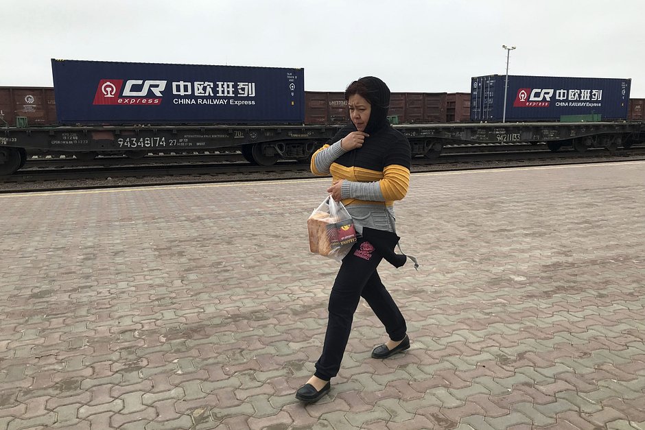 Местная жительница возле китайского железнодорожного состава с грузами на железнодорожной станции в Хоргосе на границе Казахстана с Китаем, 1 апреля 2018 года