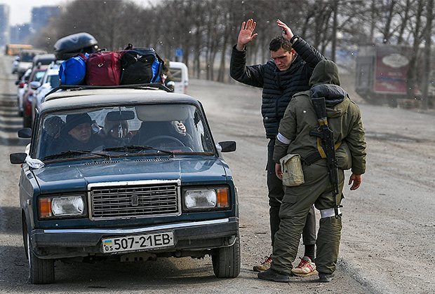 Российский военнослужащий досматривает водителя автомобиля на окраине Мариуполя