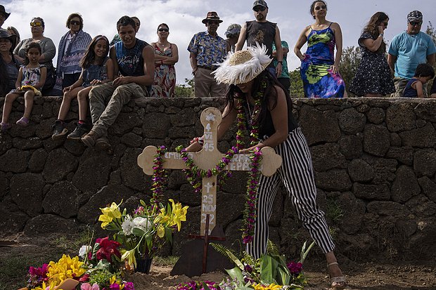 Местный житель возлагает ожерелье из цветов на могилу коневода и бывшего военного водолаза Эмилио Араки во время его похорон на кладбище Анга-Роа. Фото: Esteban Felix / AP