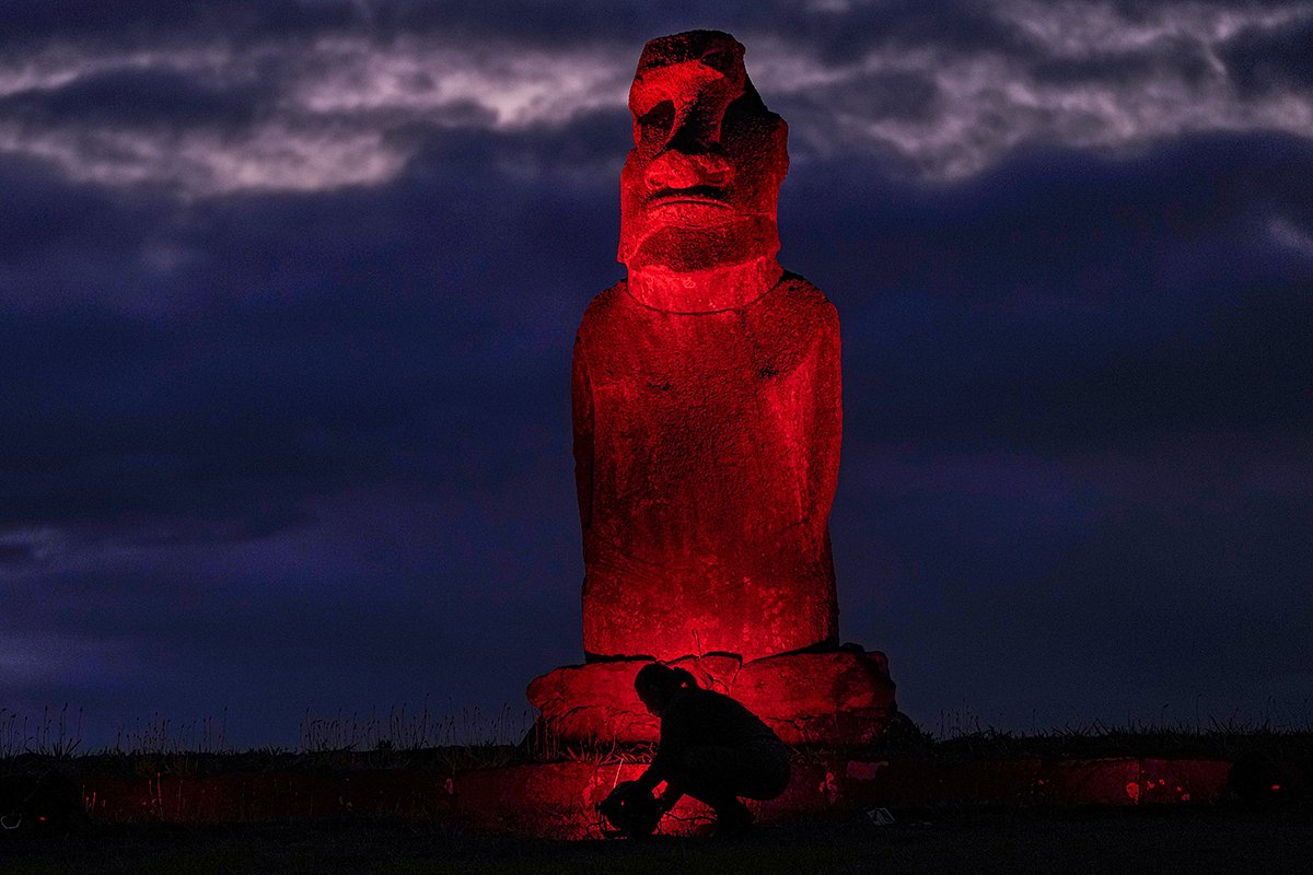 Рабочий настраивает освещение статуи моаи в преддверии Международного дня борьбы с насилием в отношении женщин