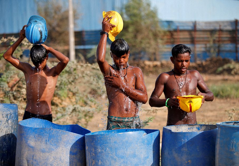 Рабочие умываются возле строительной площадки в жаркий летний день на окраине города Ахмедабад, Индия, 30 апреля 2022 года