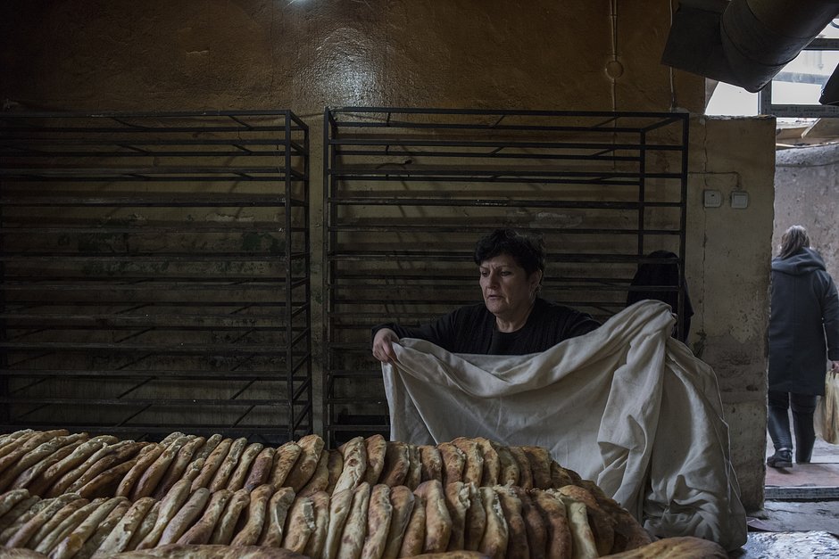 Женщина накрывает свежий хлеб в пекарне города Мартакерт (Адгере) в Нагорном Карабахе, 15 декабря 2020 года