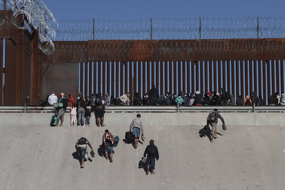 Мигранты поднимаются к стене на американо-мексиканской границе неподалеку от Эль-Пасо, 21 декабря 2022 года