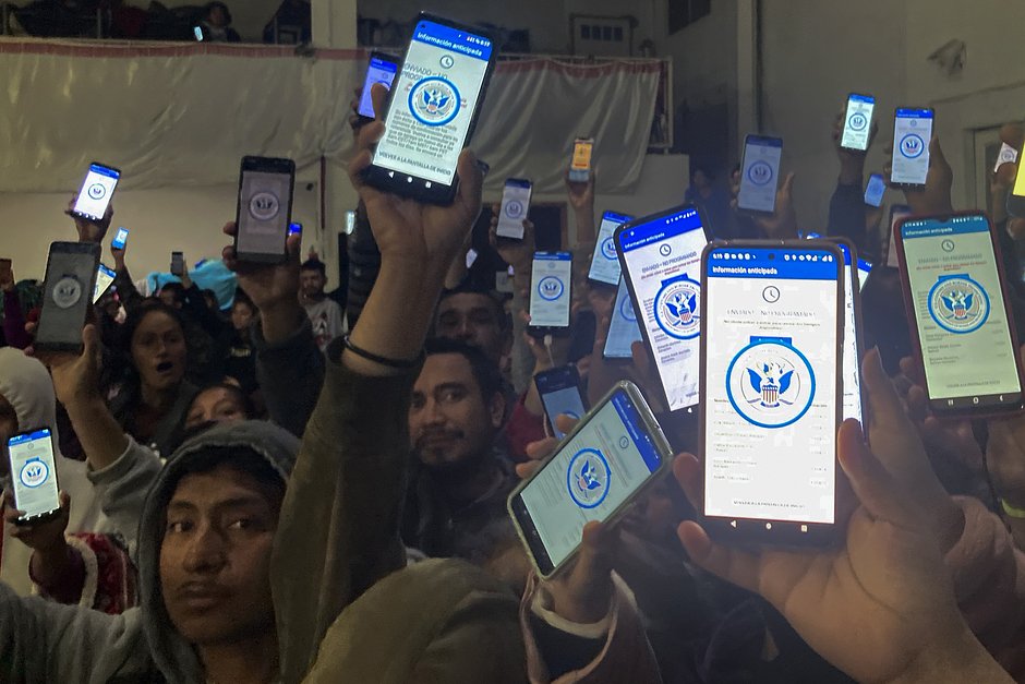 Мигранты держат телефоны с приложением Погранично-таможенной службы США, предназначенным для просителей убежища, Тихуана, Мексика, 22 января 2023 года