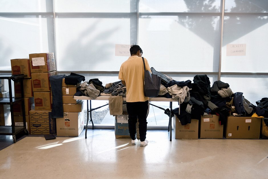 Мигрант рассматривает пожертвованную одежду во временном пункте размещения в Денвере, 6 января 2023 года