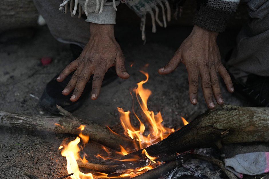 Мигрант из Венесуэлы разводит костер в холодную погоду на берегу реки Рио-Гранде на американо-мексиканской границе, 23 декабря 2022 года