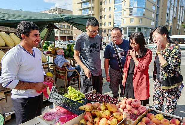  Китайские туристы покупают фрукты у уличного торговца в Санкт-Петербурге