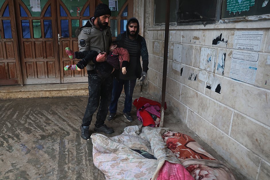 Мужчина несет тело погибшего ребенка в городе Азмарин, провинция Идлиб, северная Сирия