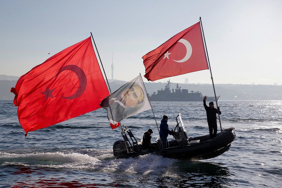 Люди на надувной лодке с турецкими национальными флагами и флагом с портретом Мустафы Кемаля Ататюрка возле дворца Долмабахче в Стамбуле, 10 ноября 2022 года