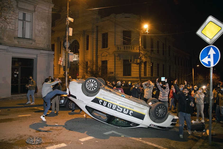 Протестующие перевернули полицейскую машину во время столкновений с полицией, 8 марта 2023 года, Тбилиси