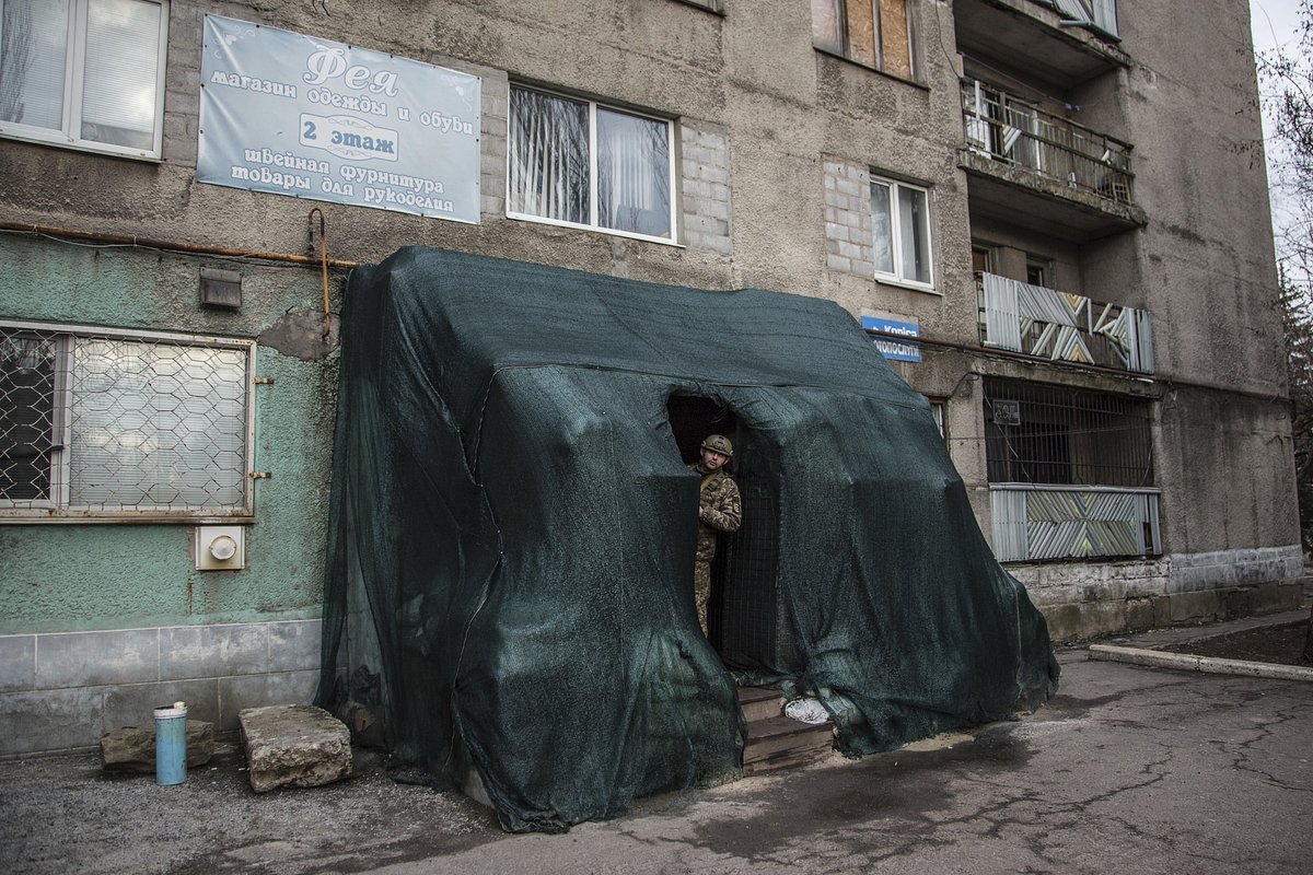 Солдат Вооруженных сил Украины выглядывает из укрытия в центре села Новолуганское, 19 февраля 2023 года