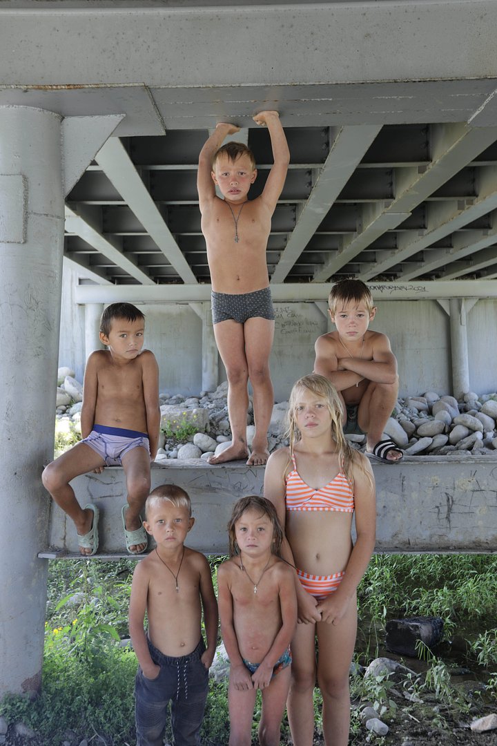 Дети в летнее время под мостом, купаются в горной речке Мультушке, а затем греются около костра. Село Мульта, Республика Алтай, 2021 год