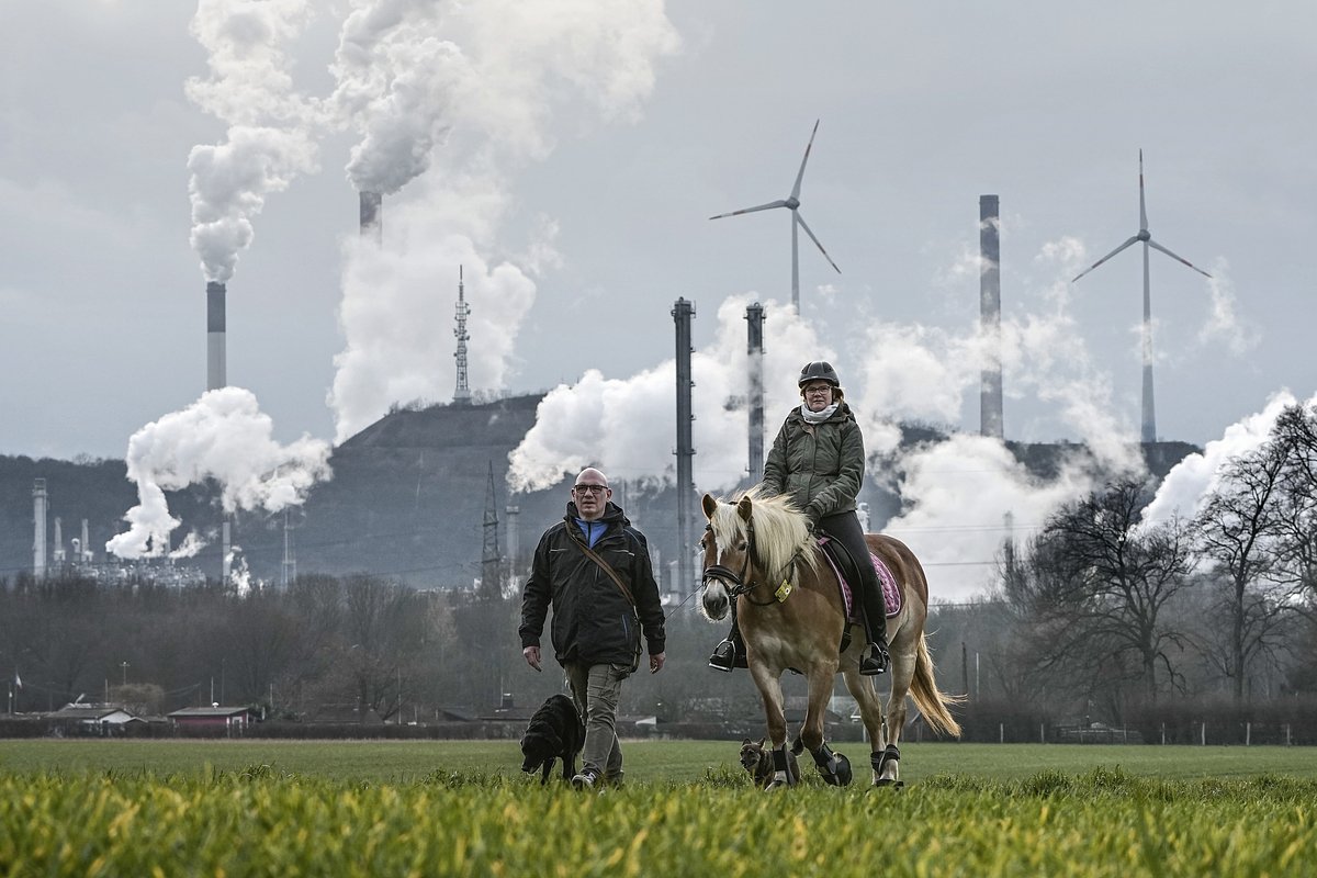Пожилая пара на прогулке на фоне нефтеперерабатывающего завода BP и угольной электростанции Uniper в Гельзенкирхене, Германия, 6 марта 2023 года