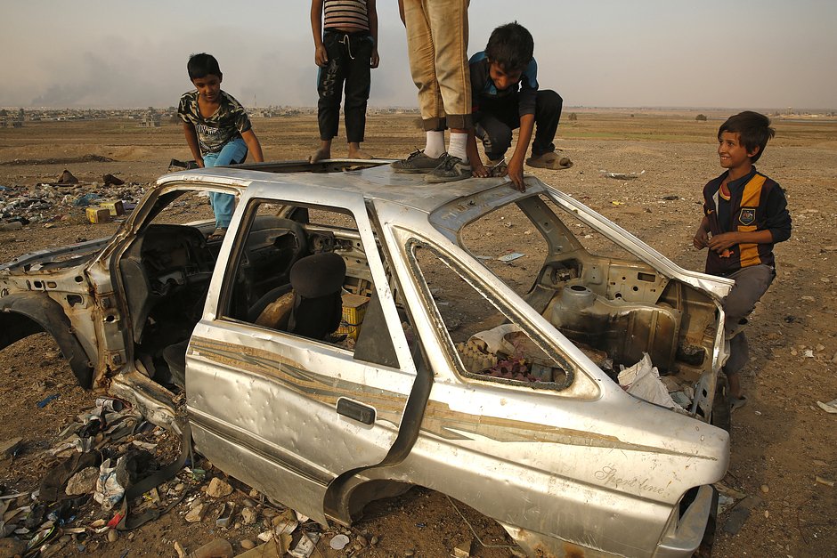 Дети у разбитой машины в деревне Хуррия, пострадавшей от боевых действий между ИГ и Ираком, 2016 год